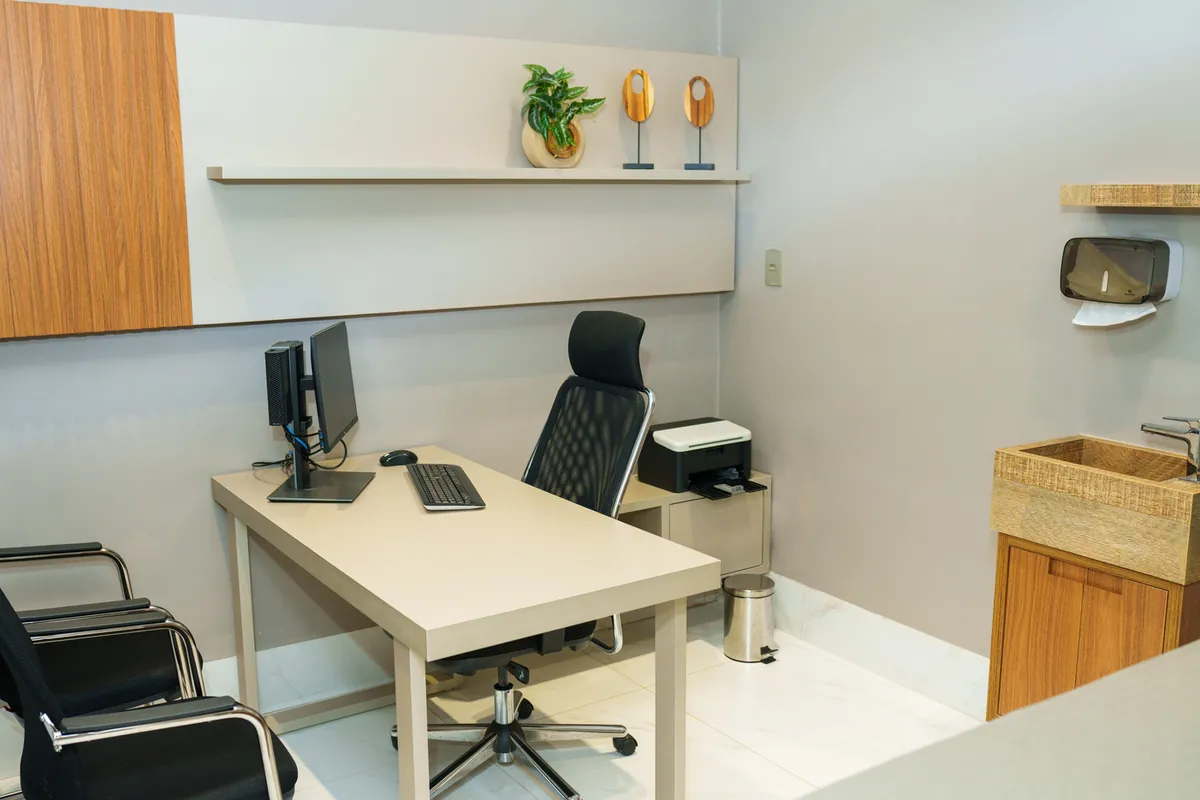 Consultório equipado com mesa, computador e pia